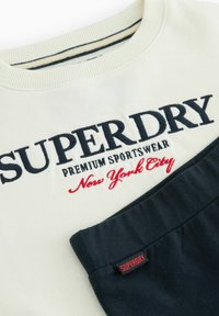 Krem hoodie s mornarskim vezom "SUPERDRY PREMIUM SPORTSWEAR New York City", koji ima kontrastni mornarski džep i rebrasti ovratnik.