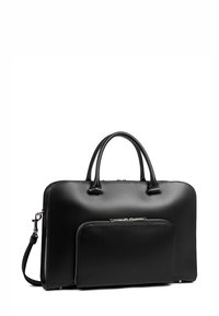 Sac en cuir noir avec une texture lisse, deux poignées et une bandoulière amovible. Il dispose d'une poche frontale zippée et d'un design minimaliste.