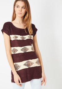 Top de punto burdeos con mangas cortas, que presenta rayas horizontales de color crema adornadas con patrones de diamantes y lentejuelas. Textura suave.