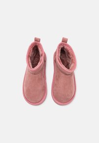 Stivaletti alla caviglia in suede rosa con una morbida fodera interna, punta arrotondata e linguetta sul retro. Suola in gomma e dettagli cuciti attorno ai bordi.
