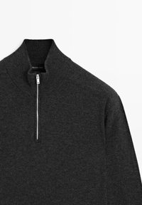 Dark gray wool sweater with a high collar and a half-zip closure. Ribbed texture on the collar and smooth body. Tag visible inside.