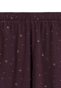 Fioletowe bawełniane spodnie z elastycznym pasem, z rozproszonym wzorem księżyców i gwiazd w jasnych kolorach. Miękka tekstura.