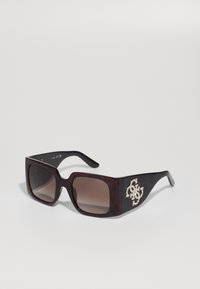 Gafas de sol de carey marrón con grandes lentes cuadrados, patillas negras texturizadas y un acento metálico con brillantes en el costado.