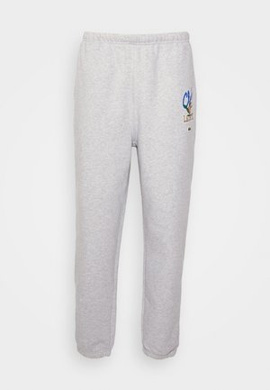 Pantalon de survêtement gris clair avec taille et poignets élastiques, comportant un petit patch logo coloré sur la partie supérieure de la cuisse gauche.