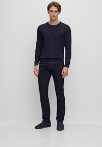 Pulover navy cu mâneci lungi, design slim-fit, cu manșete și tiv ondulate. Asortat cu pantaloni navy slim-fit și adidași albaștri, creând un look monocrom.