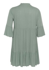 Flared sleeve dress in soft green fabric, featuring a ruffled neckline and tiered hem design for added texture and movement.