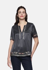 Dark satin blouse with a V-neck, featuring intricate embroidery along the hems and sleeves in colorful floral patterns. Short sleeves.