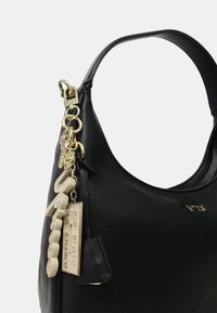 Zwarte leren schoudertas met een gestructureerde vorm, voorzien van gouden hardware, een decoratieve charme en textuurelementen.