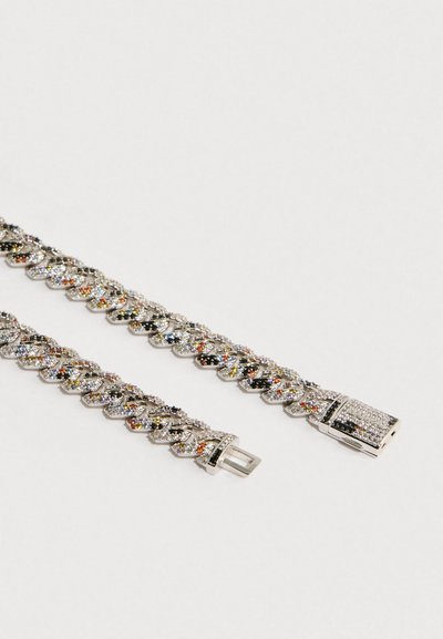 Zilverkleurige armband met schakels die in elkaar grijpen, versierd met meerkleurige edelstenen en een rechthoekige sluiting met versieringen.