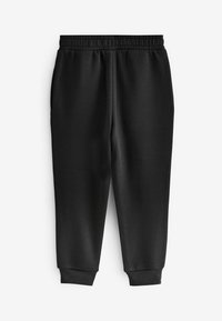 Zwarte trainingsbroek van zacht fabric met een elastische tailleband en taps toelopende benen. Heeft zijzakken en ribbelboorden bij de enkels.