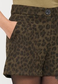 Brown leopard print shorts in soft, textured fabric with a flat waistband, button closure, and side pockets.