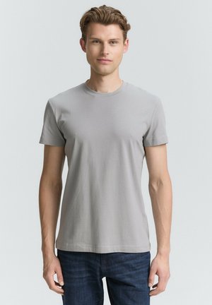 Camiseta de algodón gris con cuello redondo y mangas cortas, que presenta una textura suave y una silueta ajustada, combinada con jeans de mezclilla oscura.