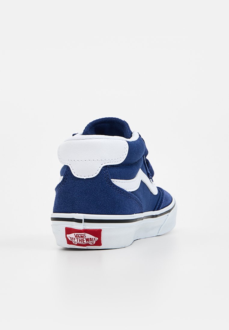 Marineblauwe suède hoge sneakers met witte accenten, voorzien van een gevoerde kraag, een contrasterende witte streep en een rood Vans-logo op de hak.