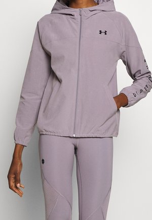 Vaaleanvioletti vetoketjullinen huppari, jossa sivutaskut ja joustavat hihansuut. Musta logo rinnassa ja hihassa. Yhdistetty samaa sarjaa oleviin leggingsseihin.