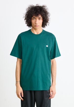 Green cotton t-shirt with a round neckline, short sleeves, and a small white logo on the left chest. Smooth texture, relaxed fit.