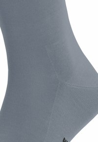 Calze grigie lavorate a maglia con una texture liscia, dotate di tallone e punta rinforzati. Un sottile motivo a coste migliora l'elasticità e la vestibilità.