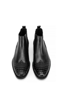 Botas Chelsea negras con parte superior de cuero liso y un patrón texturizado de cocodrilo en la punta, con lengüetas para un fácil acceso.
