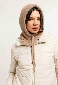 Jachetă bej cu umplutură, cu guler căptușit cu blană și o glugă tricotată măsura brună corespunzătoare, având un material texturat și detalii hardware minime.