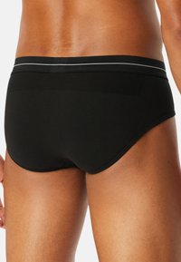 Schwarze Boxershorts aus weichem Stoff, mit einem glatten Bund mit einem kontrastierenden grauen Streifen und einem figurbetonten Schnitt.