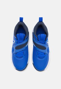 Niebieskie buty sportowe z siateczkową cholewką, kontrastującymi granatowymi akcentami, regulowanym paskiem i białą, nakrapianą podeszwą. Gładka faktura na całej powierzchni.