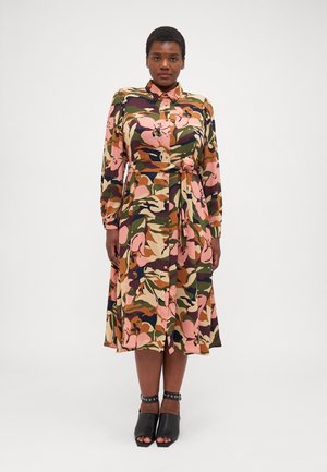 Langærmet kjole med krave og mønster i blomster-camouflage i pink, grøn og brun. Inkluderer bånd i taljen og knælængde nederdel. Sorte hæl sandaler.