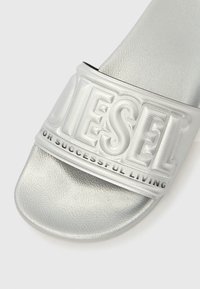 Srebrna sandala s teksturiranim, utisnutim remenom na kojem su natpisi "DIESEL" i "FOR SUCCESSFUL LIVING". Ravni potplat, sintetički materijal.