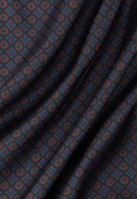 Μαύρο ύφασμα με επαναλαμβανόμενα μπλε διαμάντια και πολύχρωμα κυκλικά μοτίβα, εμφανιζόμενο με απαλές πτυχώσεις και λεπτομέρειες υφής.