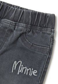 Pantalones de cintura elástica en gris oscuro con un bolsillo frontal y "Minnie" bordado en hilo gris claro cerca del bolsillo.