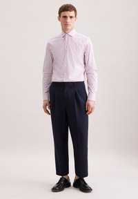 Camicia a righe rosa chiaro e bianca con colletto, abbinata a pantaloni plissettati blu navy e scarpe nere stringate. Design semplice e su misura.