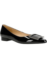 Chausson en cuir verni noir, à bout pointu, avec une accent en boucle rectangulaire argentée sur le devant. Talon bas et intérieur lisse.
