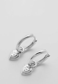 Orecchini a cerchio in argento con un pendente a forma di cuore con una piccola pietra preziosa. Il design è liscio con una finitura lucida.