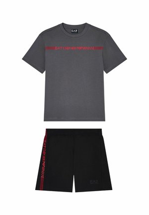 T-shirt grigio scuro a maniche corte con logo rosso EA7 Emporio Armani e pantaloncini neri con strisce laterali rosse e logo frontale sottile.