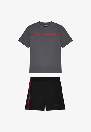T-shirt grigio scuro a maniche corte con logo rosso EA7 Emporio Armani e pantaloncini neri con strisce laterali rosse e logo frontale sottile.