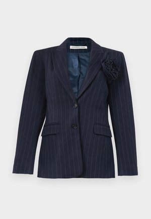 Marineblå blazer med nålestriber, to knapper, klaplommer, spids krave og en stofblomst fastgjort på venstre slag.