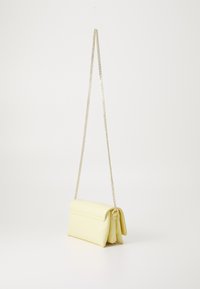 Sac à épaule en faux cuir jaune avec un design plié, une bandoulière en chaîne et un compartiment zippé à l'arrière. Texture lisse, forme compacte.