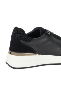 Black leather sneaker with suede heel covered in black rhinestones, white thick sole, and gold metallic accent above the sole.