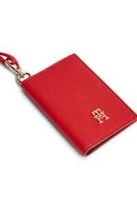 Καρτοθήκη από κόκκινο δέρμα με υφή, με χρυσό λογότυπο και χρυσό κλιπ για εύκολη μεταφορά.