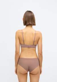 Súprava podprsenky a nohavičiek z jemnej taupe látky. Podprsenka má nastaviteľné ramienka a zapínanie na háčiky; nohavičky majú bezšvový dizajn.