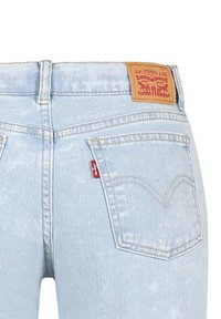 Jeans in denim azzurro chiaro con vita alta, dotati di due tasche posteriori, un'etichetta rossa e un'etichetta in pelle marrone con il marchio sul retro.