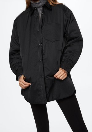 Giacca camicia nera, over size, realizzata in tessuto leggero e liscio. Presenta una tasca sul petto e chiusura con bottoni, con una vestibilità comoda.