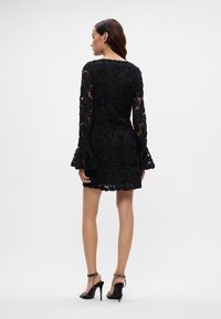 Melnas mežģīņu kleitas ar garām, izplestām piedurknēm un izšūtiem ziedu rakstiem. Kleitai ir pieguļošs bodijs un izplesta svārku daļa ar viļņotu apakšmalu.