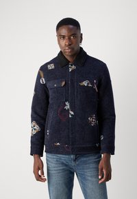 Ναυτικό μπλε μπουφάν με υφασμάτινη υφή, διαθέτει λουλουδάτα και γεωμετρικά κεντήματα, με μαύρη γούνα στη λαιμόκοψη και διπλές τσέπες στο στήθος.