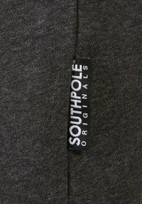 Sötétszürke pamut szövet sima textúrával, az oldalán fehér betűkkel „SOUTHPOLE ORIGINALS” feliratú fekete címkével.