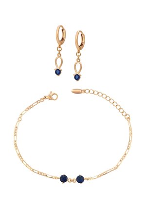 Cercei aurii tip cerc cu zale și talismane cu mărgele albastre, asortați cu o brățară delicată din lanț auriu cu două mărgele albastre.