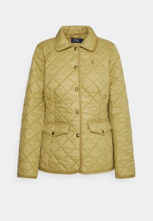 Veste matelassée jaune clair avec col, fermetures à pression, deux poches avant et bordure contrastante le long des bords. Dispose d'un petit logo.