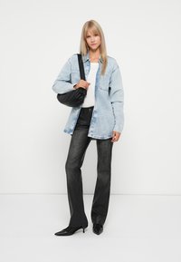 Světle modrá džínová oversized košile, bílý tričko, černé kalhoty s vysokým pasem a rozšířenými nohavicemi, černá kabelka přes rameno, špičaté podpatky.