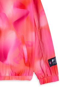 Chaqueta de degradado rosa con tejido ligero y suave. Cuenta con un dobladillo y puños fruncidos, además de un bolsillo y un parche con el logo en la manga.