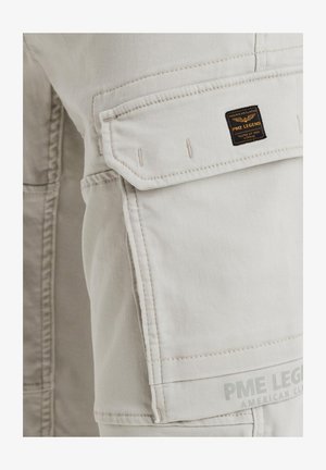 Pantaloni cargo beige con una tasca laterale, cuciture rinforzate e un'etichetta nera "PME Legend" sul davanti. Tessuto testurizzato, design funzionale.