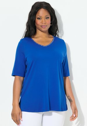 Haut bleu royal à manches courtes avec un décolleté en V, comportant une bordure décorative autour de l'encolure. Fabriqué en tissu doux et lisse.