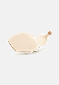 Sandale blanche avec une semelle intérieure texturée couleur tan, des brides supérieures lisses et un profil plat. La semelle offre une légère adhérence pour plus de traction.